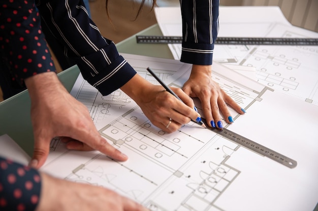 De cerca con las manos de dos arquitectos que dibujan algo en el plano de una casa. planos y plan de nueva construcción