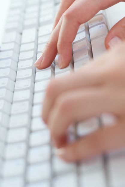 Cerca de manos escribiendo en el teclado en el lugar de trabajo