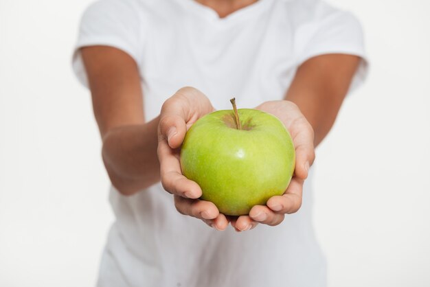 Cerca de manos femeninas mostrando manzana verde