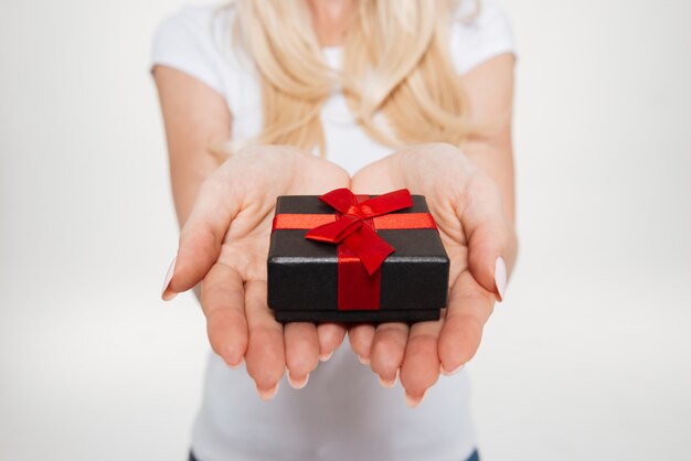 Cerca de manos femeninas con pequeña caja de regalo