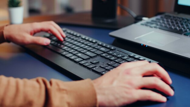 Cerca de las manos del ingeniero escribiendo en el teclado en la oficina en casa.