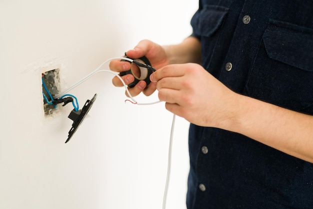 Cerca de las manos de un joven reparando el interruptor roto y haciendo renovaciones en el hogar