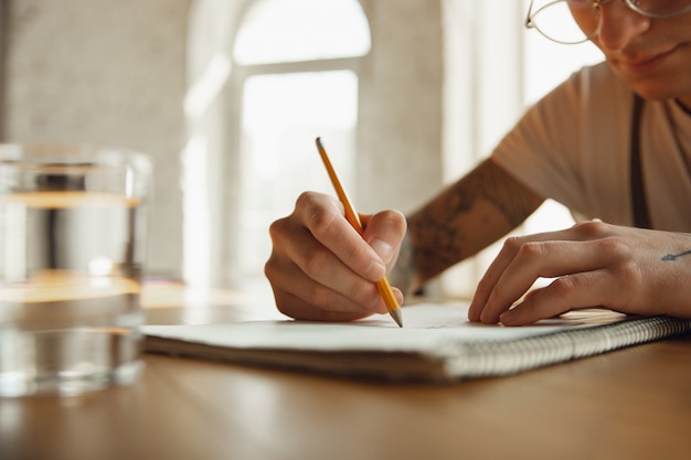 Cerca de manos masculinas escribiendo en un papel vacío, educación y concepto de negocio