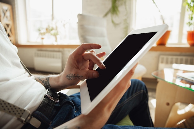 Cerca de manos masculinas con tableta con pantalla en blanco