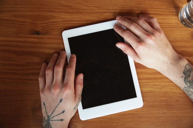Cerca de manos masculinas con tableta con pantalla en blanco
