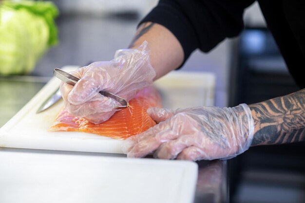 Cerca de mans manos cortando pescado para sushi