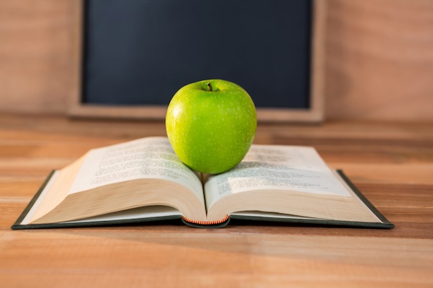 Cerca de la manzana verde con el libro abierto