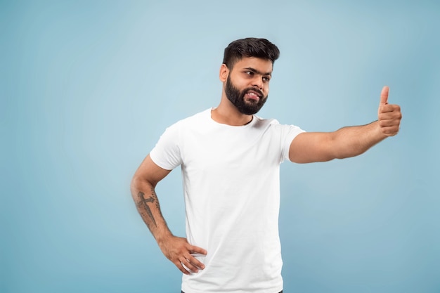 Cerca de medio cuerpo retrato de hombre joven con camisa blanca sobre azul