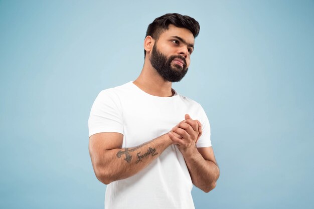 Cerca de medio cuerpo retrato de hombre joven con camisa blanca sobre azul