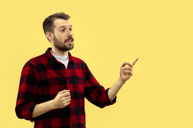 Cerca de medio cuerpo retrato de hombre joven en camisa en el espacio amarillo. Las emociones humanas, el concepto de expresión facial. Vista frontal. Colores de moda. Espacio negativo