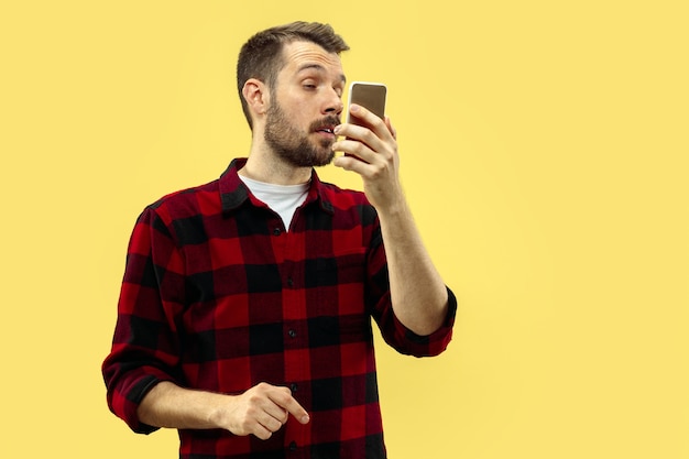 Foto gratuita cerca de medio cuerpo retrato de hombre joven en camisa en el espacio amarillo. las emociones humanas, el concepto de expresión facial. vista frontal. colores de moda. espacio negativo