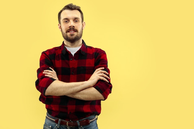 Cerca de medio cuerpo retrato de hombre joven en camisa en el espacio amarillo. Las emociones humanas, el concepto de expresión facial. Vista frontal. Colores de moda. Espacio negativo