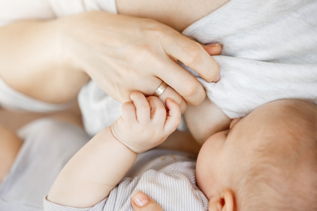 Cerca del momento íntimo madre amamantando a su hijo recién nacido. Escena de inocencia y protección. Concepto de familia, maternidad y estilo de vida.