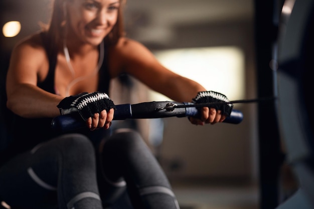 Cerca de una mujer atlética haciendo ejercicio en una máquina de remo mientras entrena en el gimnasio