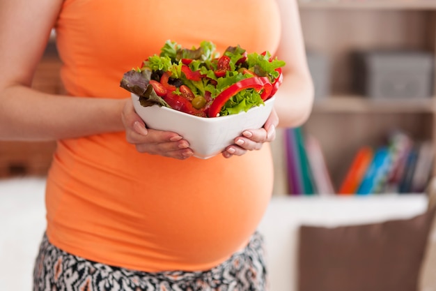 Foto gratuita cerca de la mujer embarazada con ensalada de verduras