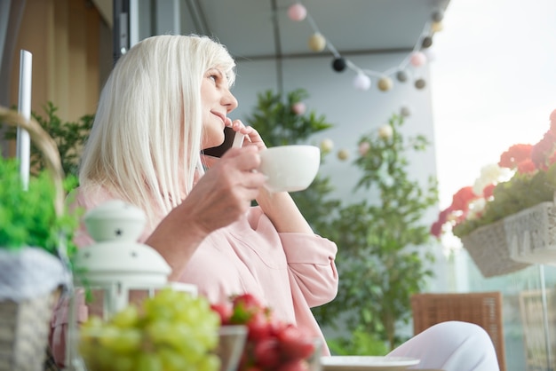 Cerca de mujer madura disfrutando de un buen café en el balcón