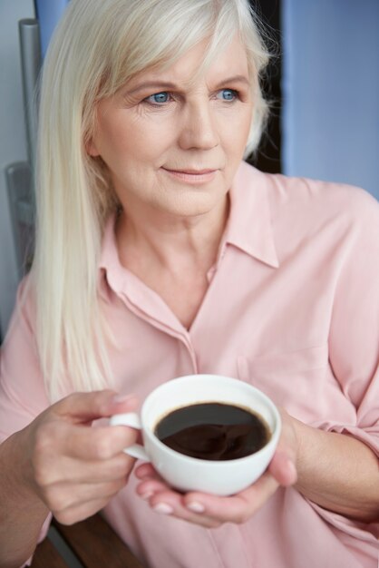 Cerca de mujer madura disfrutando de un buen café en el balcón