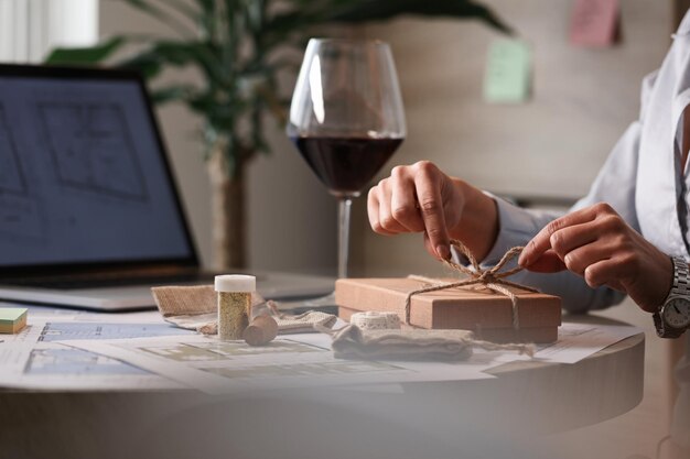 Cerca de una mujer de negocios envolviendo un regalo y atando una cinta en la oficina