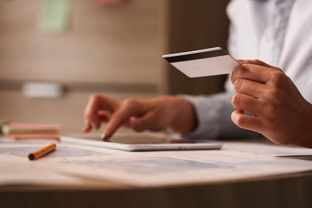 Cerca de una mujer de negocios con tarjeta de crédito revisando su cuenta bancaria en una tableta digital