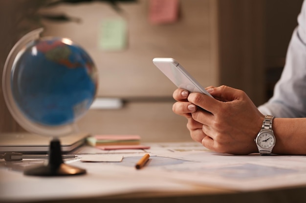 Cerca de una mujer de negocios usando un teléfono inteligente y escribiendo un mensaje en la oficina