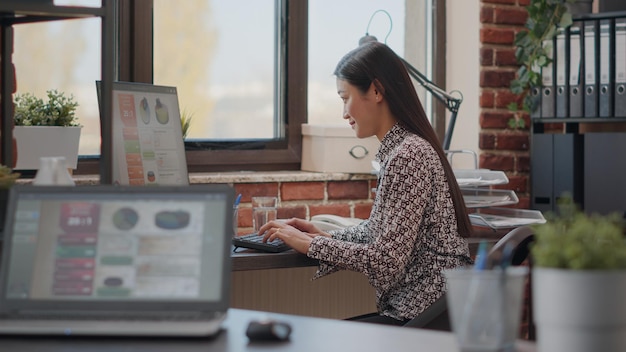 Cerca de una mujer que trabaja en la planificación de proyectos con la computadora, diseñando una estrategia de marketing y gestión para el desarrollo en la oficina. Empleado que utiliza análisis para el crecimiento del negocio de inicio.