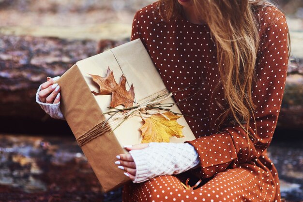 Cerca de mujer sosteniendo regalo envuelto otoñal