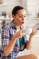 Foto gratuita cerca de mujer sosteniendo una taza de té verde caliente tratando de beberlo