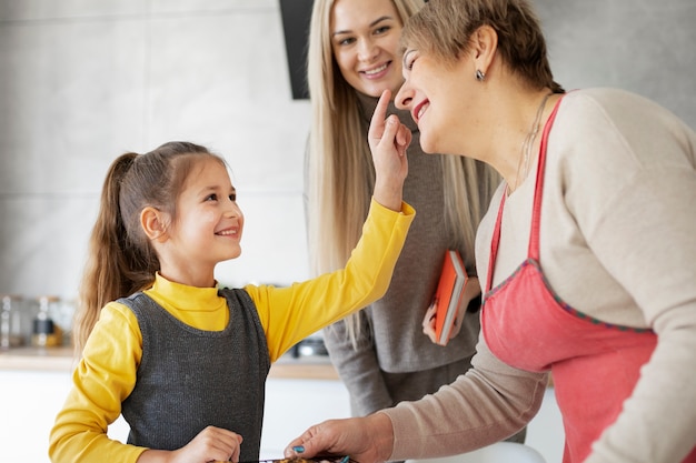 Cerca de niña cocinando con su madre y su abuela