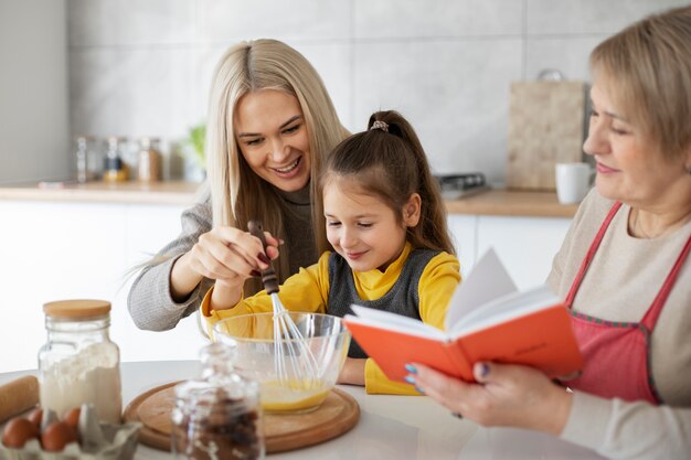 Cerca de niña cocinando con su madre y su abuela