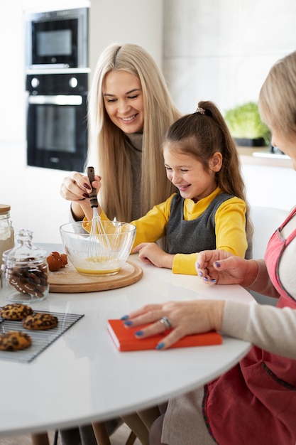 Cerca de niña cocinando con su madre y su abuela