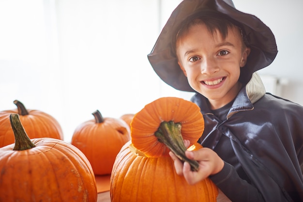 Cerca de niño joven y feliz tallando calabazas