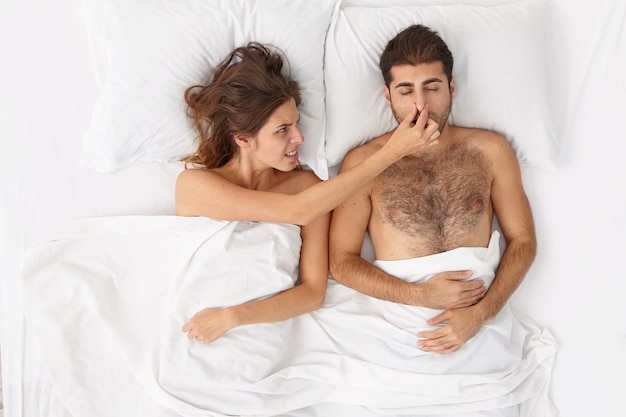 Cerca de la pareja acostada en la cama bajo una manta blanca