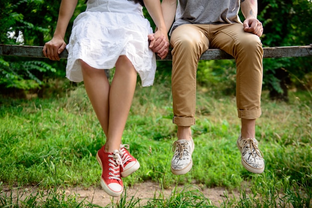 Foto gratuita cerca de la pareja en keds sentado en el banco.