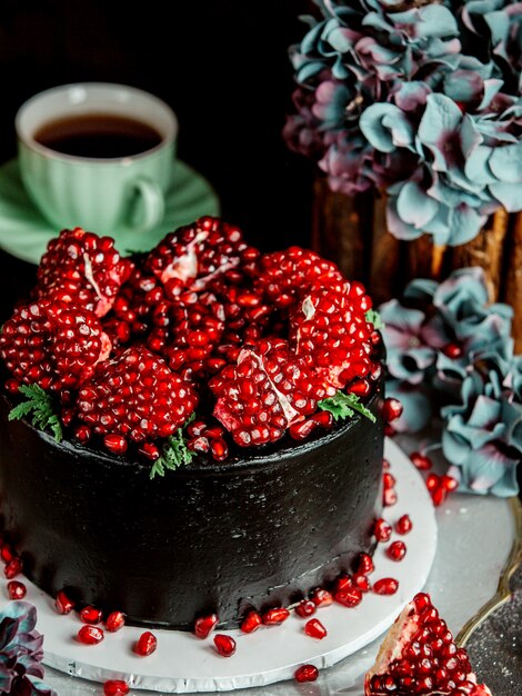 Cerca de pastel de chocolate negro cubierto con semillas de granada