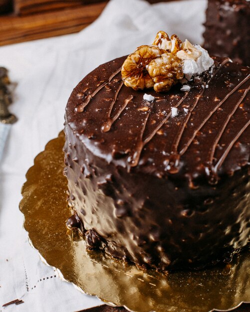 Cerca de pastel cubierto de chocolate y nueces sobre la mesa