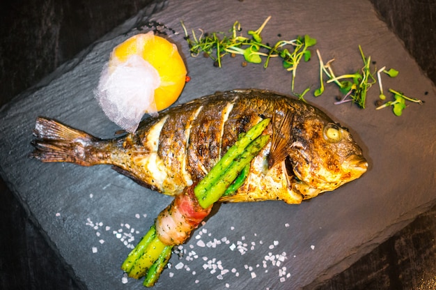 Cerca de pescado a la plancha decorado con verduras.