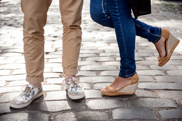 Cerca de las piernas de la pareja en keds de pie en la calle.