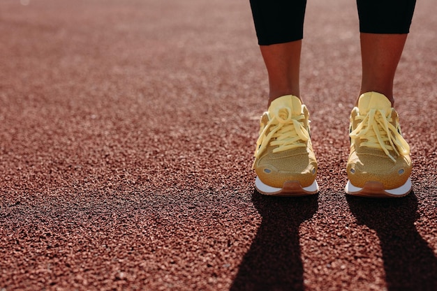 Cerca de pies femeninos en zapatillas amarillas en el estadio