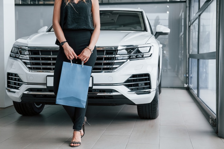 Foto gratuito cerca de las puertas. chica y coche moderno en el salón. durante el día en interiores. comprar vehículo nuevo