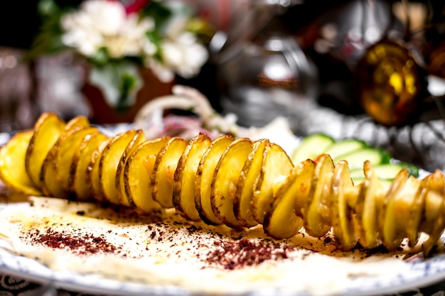 Cerca de rodajas de patata kebab en brocheta de acero fino con trozos de grasa de cordero