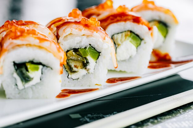 Cerca de rollos de sushi con algas pimiento y pescado cubierto de camarones