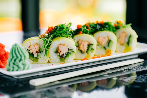 Cerca de rollos de sushi con salmón frito y pepino cubierto con algas y tobiko rojo