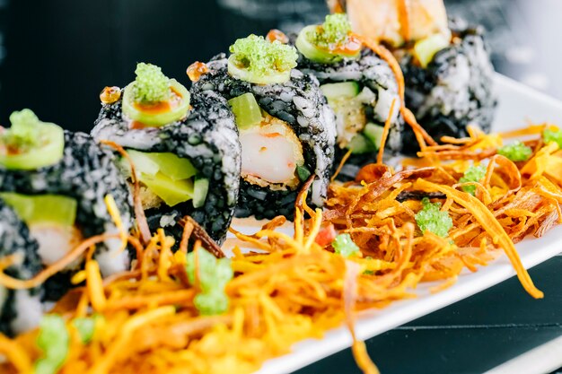 Cerca de rollos de sushi con tempura y aguacate cubierto con arroz teñido negro