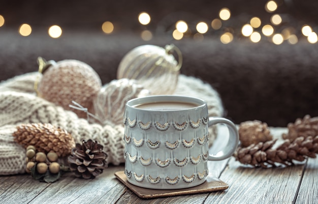 Cerca de la taza de Navidad y decoración festiva sobre fondo oscuro borroso con bokeh.