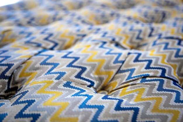 Cerca de la textura del sofá suave moteado con botones hundidos. Idea y variante de tejido para tapizado de sofá.