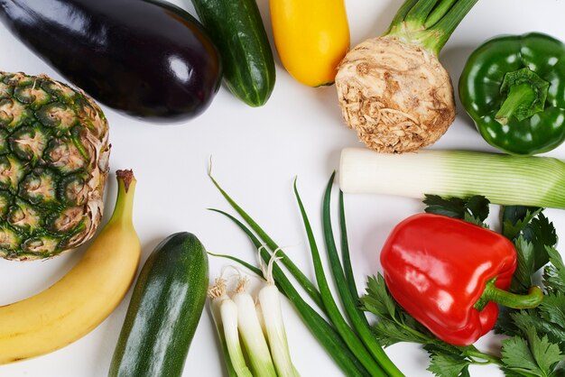 Cerca de variadas verduras y frutas sobre fondo blanco.