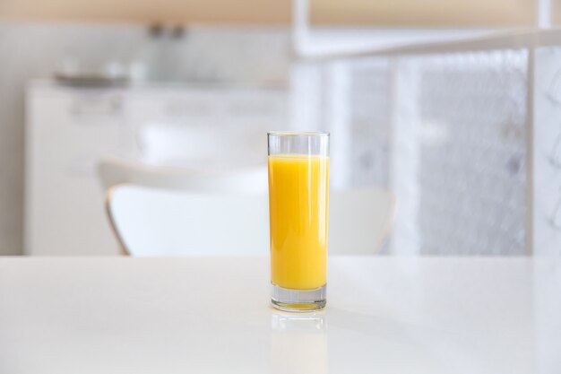 Cerca de un vaso de jugo de naranja sobre un fondo claro borroso del interior de un café.