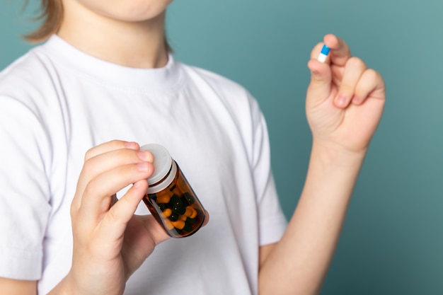 de cerca, ver niño lindo dulce adorable celebración pastillas en camiseta blanca sobre azul