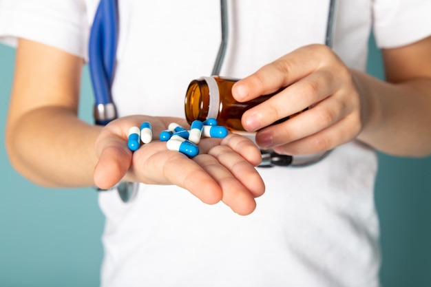 de cerca, ver niño con pastillas azules en camiseta blanca