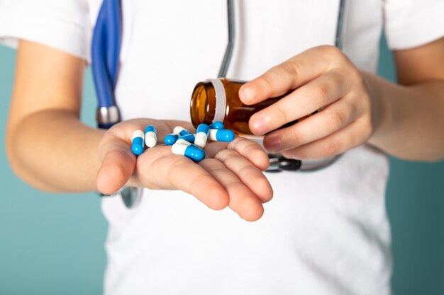 de cerca, ver niño con pastillas azules en camiseta blanca